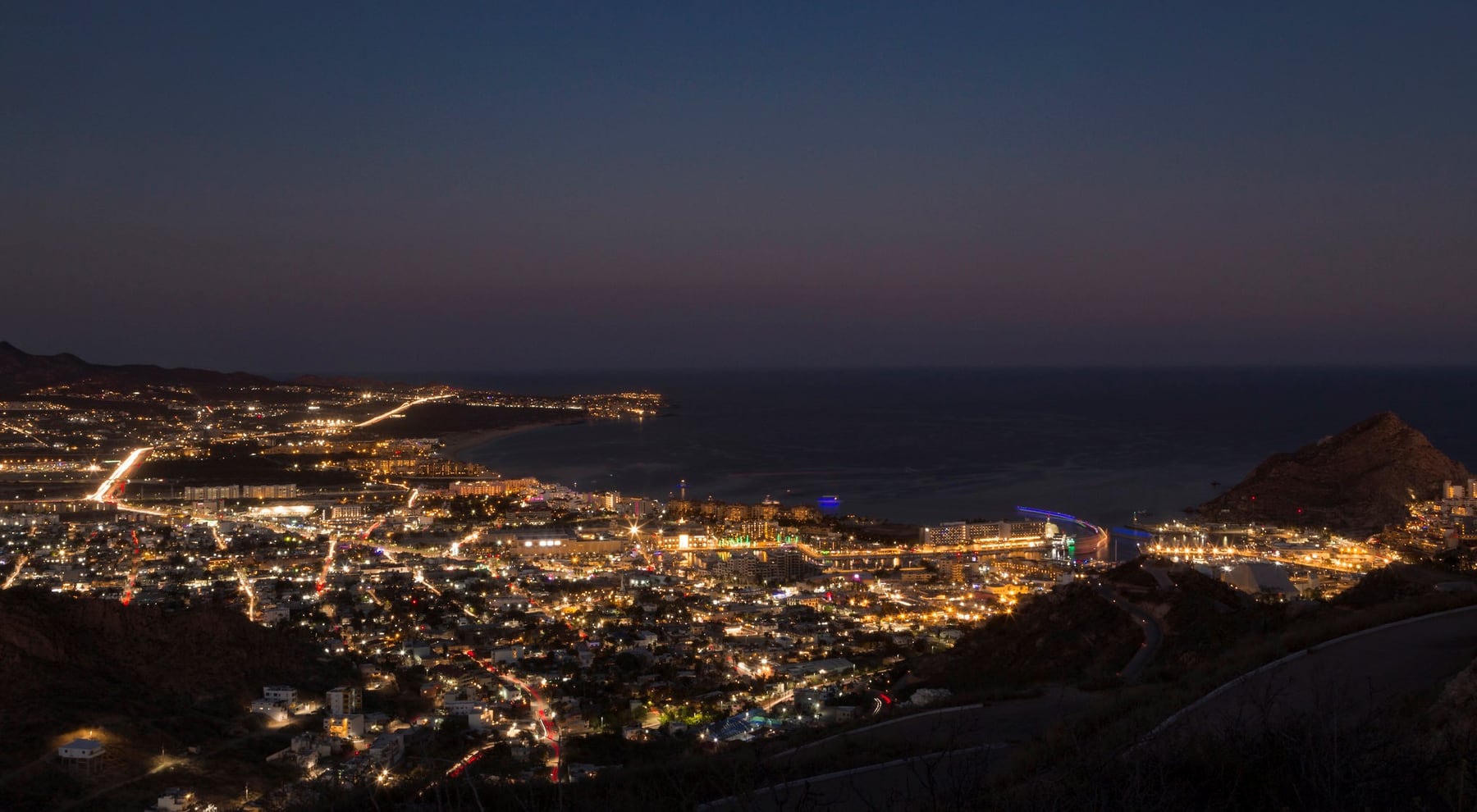 Aerial nighttime view of illuminated streets and buildings in Cabo San Lucas.