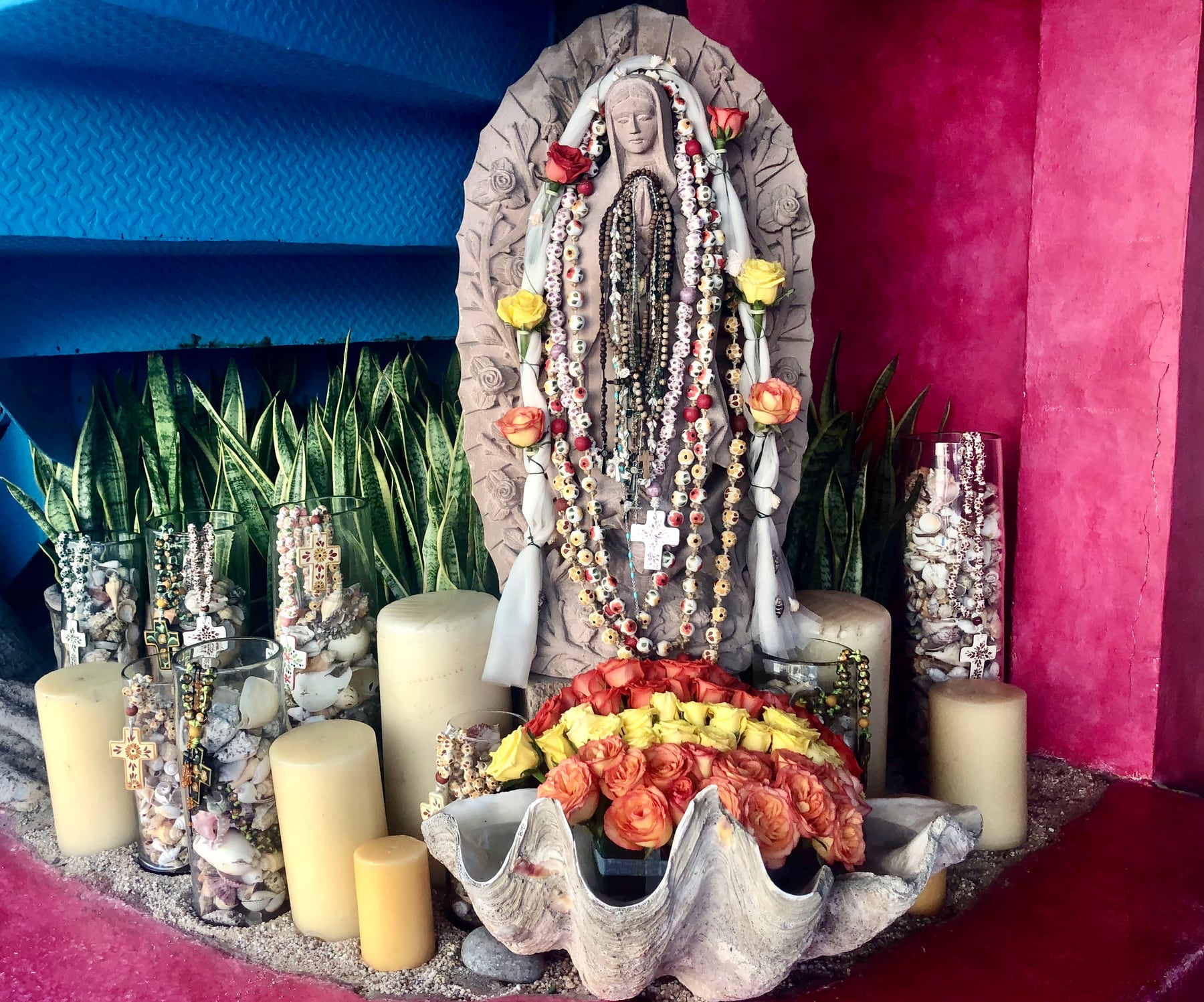 Decorative shrine with flowers, candles, shells, and colorful walls at The Office on the Beach.
